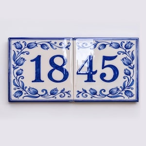 May include: Two rectangular ceramic tiles placed side by side, featuring a white background with a blue border and a blue floral tulip vine pattern. The tiles display the number 1845 in a large, bold, blue serif font centered on the surface.