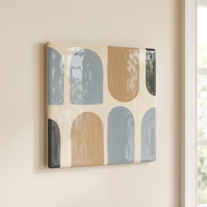 May include: A rectangular wall art piece featuring a glossy finish with a repeating pattern of rounded arch shapes in muted shades of dusty blue, tan, and charcoal gray set against a solid cream-colored background with a smooth surface.
