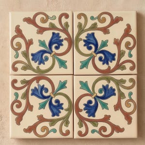 May include: A set of four square ceramic tiles arranged in a grid, each featuring an identical cream-colored background with a symmetrical floral pattern in shades of deep blue, muted green, and terracotta brown with swirling vine-like motifs.