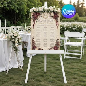 Puede incluir: Un cartel de plan de asientos de boda sobre un caballete blanco, con fondo crema, detalles florales burdeos, texto dorado y un arreglo de rosas blancas. El cartel muestra el texto Seating Chart, Isabella & William y listas de mesas.