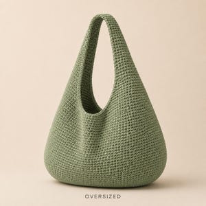 May include: An oversized sage green crochet hobo bag with a single integrated shoulder strap and a dense, textured stitch pattern. The word OVERSIZED is printed in small, dark capital letters centred below the base of the bag.