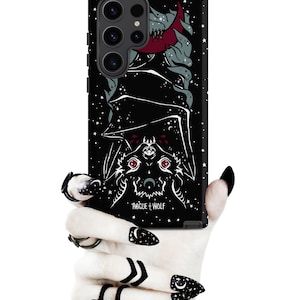 May include: Black phone case with a graphic of a bat with a skull face and red eyes. The bat is hanging upside down with its wings spread out. The background is a black starry night with a crescent moon. The text "Rogue + Wolf" is printed on the case.