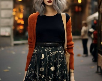 May include: A woman with silver hair is wearing a black top, a rust-colored cardigan, a black skirt with a moon and floral print, and a brown leather bag.