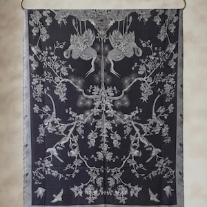 May include: A rectangular scarf in dark charcoal gray featuring a symmetrical white print of cranes, flowering branches, and smaller birds. The scarf has a solid gray border with a repeating bird pattern along the bottom edge and a fringed hem.