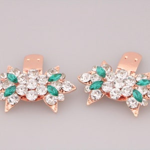 Puede incluir: Un par de clips para zapatos de oro rosa con un dise&ntilde;o floral. Los clips est&aacute;n adornados con diamantes de imitaci&oacute;n transparentes y verdes.