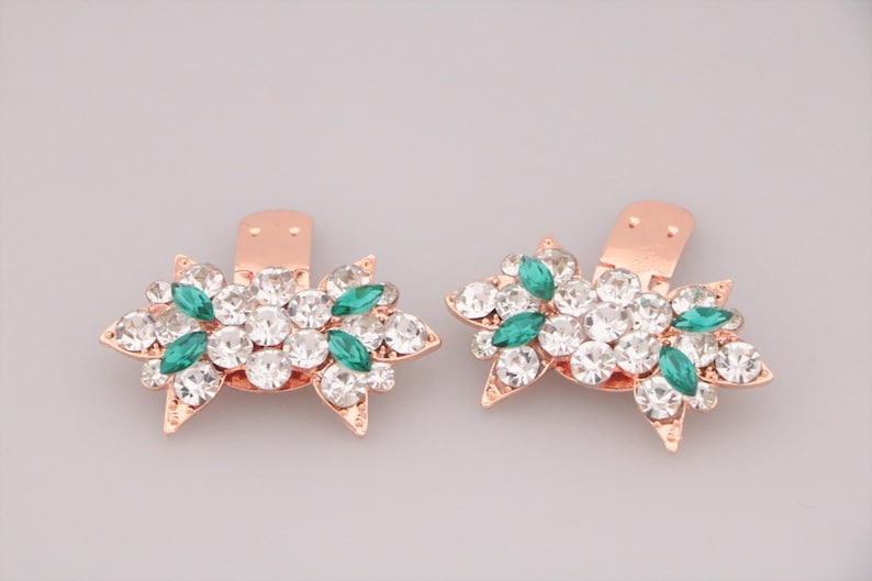 Puede incluir: Un par de clips para zapatos de oro rosa con un dise&ntilde;o floral. Los clips est&aacute;n adornados con diamantes de imitaci&oacute;n transparentes y verdes.