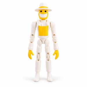 May include: A white and yellow articulated action figure featuring a wide, toothy grin, a fedora-style hat, and a chest plate. The figure has a bright yellow head and hands, with a white body, arms, and legs, standing in a neutral pose.