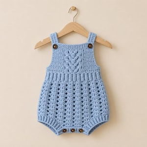 May include: A light blue crochet romper featuring a textured cable knit pattern on the chest, a ribbed waistband, and a lacy openwork stitch on the lower section. The garment includes two brown buttons at the shoulder straps and three at the crotch.