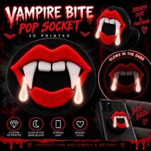 May include: A 3D printed phone grip featuring a red mouth with white fangs and dripping blood accents. The design includes text reading VAMPIRE BITE POP SOCKET, 3D PRINTED, GLOWS IN THE DARK, CUSTOM 3D PRINTED, GLOW IN THE DARK BLOOD, STRONG GRIP, and SPOOKY STYLE.