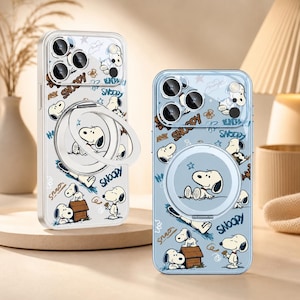 Può includere: Due cover trasparenti per smartphone con un motivo ripetuto di Snoopy in varie pose, tra cui seduto vicino a una cuccia. Ogni cover include un supporto ad anello magnetico circolare sul retro e un'apertura per l'obiettivo della fotocamera.