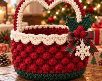 May include: A round, deep red crocheted basket with a dark green base and a cream-colored scalloped rim. The handle is heart-shaped and cream-colored. It is decorated with a green crocheted holly leaf, red berries, a plaid bow, and a white snowflake.