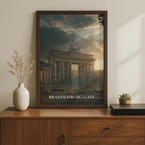 May include: A framed wall art print featuring a dark, atmospheric depiction of the Brandenburg Gate under a cloudy sky at sunset. The text BRANDENBURG GATE is printed in white capital letters at the bottom of the image within the dark brown frame.