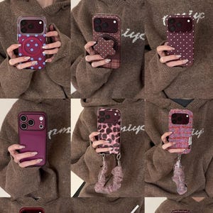 May include: A collection of nine smartphone cases in various designs, including polka dots, leopard print, solid maroon, and textured patterns. Several cases feature attached wrist straps, scrunchies, or pop-out grips, showcasing diverse styles for mobile devices.