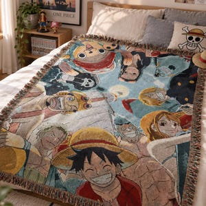 Peut inclure: Un plaid tissé présentant une impression graphique colorée de l'ensemble des personnages de l'anime One Piece, incluant Luffy, Zoro, Nami et Chopper, avec une bordure à franges. Le motif affiche plusieurs personnages en mosaïque.