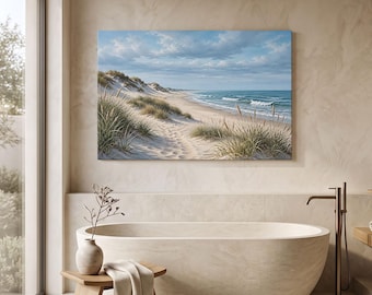 May include: A rectangular wall art print depicting a coastal landscape with sand dunes, tall beach grass, and a blue ocean under a cloudy sky. The scene is displayed above a smooth, oval-shaped beige bathtub and a small wooden stool with a towel.