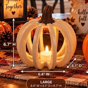 May include: A cream-colored, open-frame pumpkin decoration with a brown stem and a white LED tea light inside. The pumpkin measures 6.4 inches wide, 6.1 inches deep, and 6.7 inches high, as indicated by the text and arrows on the image.