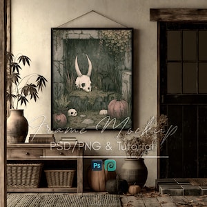 May include: A framed wall art print featuring a horned skull, a small black creature, and pumpkins in a stone garden setting. The artwork includes the text Frame Mockup PSD/PNG & Tutorial. The print is displayed in a room with a wooden console table.