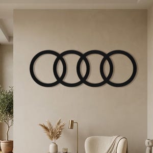 May include: A black wall art piece consisting of four interlocking circles arranged in a horizontal row. The design features thin, uniform circular frames that overlap each other, creating a continuous chain-like pattern mounted on a wall.