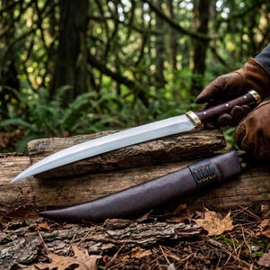 May include: A long, sharp steel blade with a dark wooden handle and brass bolster, held by brown leather gloves. A matching dark brown leather sheath with stitched detailing lies horizontally on a textured log surface.
