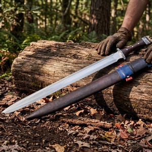 Può includere: Una spada in acciaio a doppio taglio con impugnatura in legno scuro, dettagli in metallo argentato e un fodero in pelle marrone scuro abbinato con una sezione del colletto in pelle blu e un piccolo dettaglio rosso, appoggiata su un tronco.