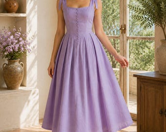 May include: A lavender midi dress featuring a square neckline, shoulder straps with tie details, and a fitted bodice with a vertical row of small matching buttons. The skirt is pleated at the waist, creating a full, flared silhouette that falls below the knee.