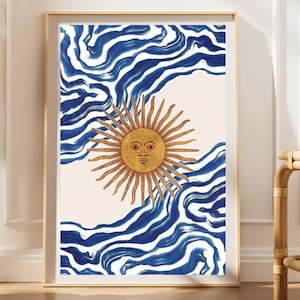 May include: A framed vertical wall art print featuring a central golden sun with a human face and radiating beams, set against a cream-colored background. The top and bottom sections display abstract, flowing dark blue brushstroke patterns.