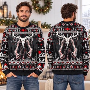 May include: A black long-sleeve crewneck sweater featuring a white skull-headed creature with large antlers, surrounded by red and white geometric patterns, moon phases, wolves, and campfire motifs across the front and back.