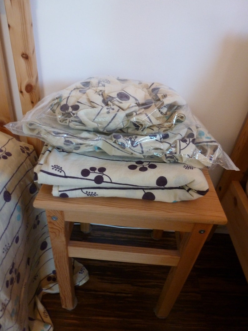 Puede incluir: Un taburete de madera con una tela estampada en blanco y marr&oacute;n en la parte superior. La tela tiene un dise&ntilde;o floral con peque&ntilde;os puntos negros.