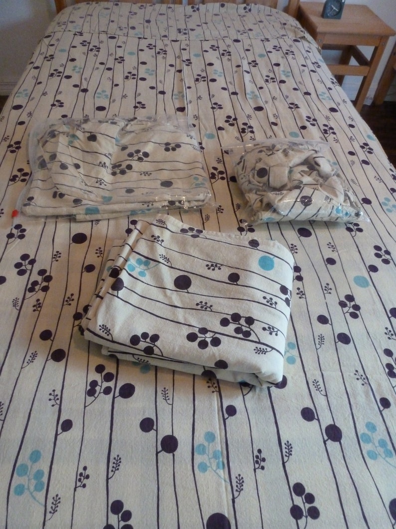 Puede incluir: Tres s&aacute;banas de tela con estampado blanco y azul dobladas sobre un edred&oacute;n con estampado blanco y azul. Las s&aacute;banas tienen un dise&ntilde;o de l&iacute;neas negras y peque&ntilde;os c&iacute;rculos azules y negros.
