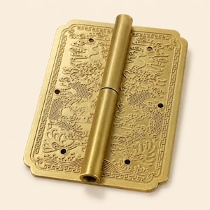Peut inclure: Une charnière rectangulaire en laiton présentant un motif de dragon en relief complexe sur sa surface. La plaque métallique possède un cylindre central et quatre petits trous de vis circulaires placés près des coins de la bordure ornée.