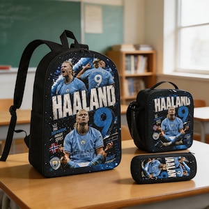May include: A black backpack, lunch bag, and pencil case set featuring Erling Haaland in a light blue Manchester City jersey. The items display the text HAALAND, the number 9, the Manchester City crest, and the phrase The Terminator Never Stops.