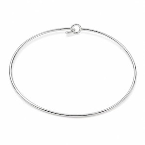 May include: A thin, circular silver bangle bracelet featuring a simple hook and eye closure mechanism. The bracelet is constructed from a smooth, polished silver wire that forms a continuous, minimalist loop when fastened securely at the top.