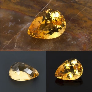 May include: Three pear-shaped gemstones, each with a different cut and facet pattern. The gemstones are a vibrant yellow-orange color and have a glossy finish.