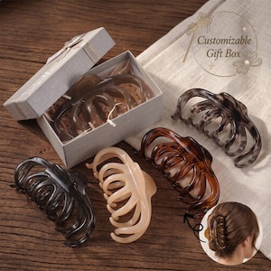 May include: A set of five claw hair clips in various translucent colors including black, brown, beige, and gray, with one clip inside a gray gift box labeled Customizable Gift Box. A small circular inset shows a clip worn in hair.