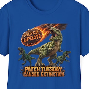 May include: A royal blue short-sleeve t-shirt featuring a graphic of three green dinosaurs looking up at a flaming meteor. The meteor is labeled PATCH UPDATE, and the text below the dinosaurs reads PATCH TUESDAY CAUSED EXTINCTION in orange.
