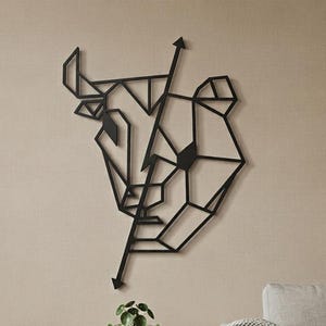 Puede incluir: Una pieza de arte mural de metal negro con un diseño geométrico y lineal de una cabeza de toro. La escultura está compuesta por líneas finas interconectadas que forman una silueta abstracta y angular del animal sobre la pared.
