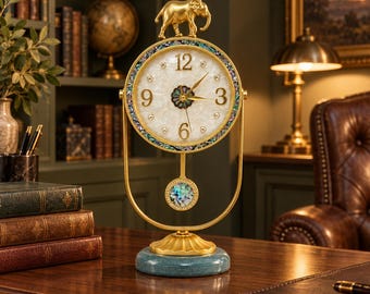 May include: A gold-toned table clock featuring a white mother-of-pearl face with gold numerals, an iridescent shell border, and a gold elephant figurine on top. The clock has a swinging pendulum with an iridescent inlay and a teal base.