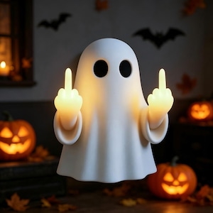 May include: A white ghost-shaped lamp with two black circular eyes, emitting a warm yellow glow from its hands which are raised in a middle finger gesture. The smooth, matte-finished figure stands upright, providing illumination through its raised arms.