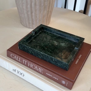 May include: A rectangular dark green marble tray with a smooth, polished finish and a recessed centre. The tray features distinct natural veining patterns throughout the stone surface, showcasing deep forest green tones and subtle lighter mineral streaks.