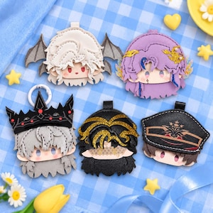 May include: Five character-themed keychains made of faux leather. The top row features a white-haired figure with bat wings and a purple-haired figure with gold accents. The bottom row shows a grey-haired figure with a black crown, a black-haired figure with gold glitter hair, and a brown-haired figure wearing a black military-style cap.