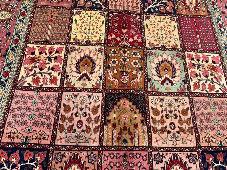 May include: A rectangular area rug featuring a grid of square panels, each displaying intricate floral and botanical motifs in shades of pink, red, cream, brown, and green. The design includes stylized trees, vases, and birds within a dark border.