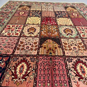 May include: A large rectangular area rug featuring a grid of square panels, each decorated with intricate floral, botanical, and architectural motifs in shades of pink, red, navy blue, cream, and gold, finished with a thin fringe along the edge.