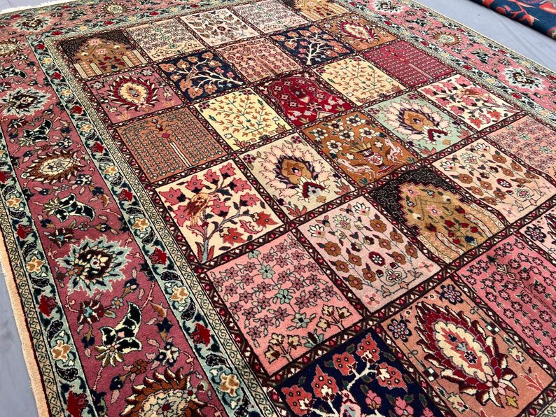 May include: A rectangular area rug featuring a patchwork design of various square panels. Each square displays intricate floral and botanical motifs in shades of pink, red, cream, navy blue, and gold. The rug has a wide, ornate floral border.