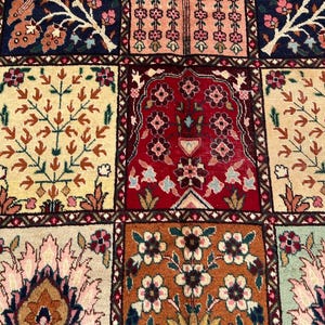 May include: A woven rug featuring a grid of rectangular panels, each displaying distinct floral and tree motifs in a palette of deep red, navy blue, cream, orange, and soft pink. The intricate patterns include stylized blossoms and foliage.