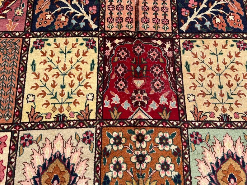 May include: A woven rug featuring a grid of rectangular panels, each displaying distinct floral and tree motifs in a palette of deep red, navy blue, cream, orange, and soft pink. The intricate patterns include stylized blossoms and foliage.