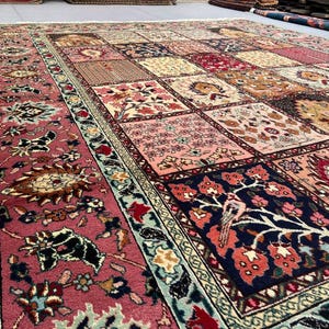 May include: A large rectangular area rug featuring a patchwork design of various square panels. Each square displays intricate floral, botanical, and bird motifs in a palette of deep red, navy blue, cream, pink, and sage green, framed by a wide border.