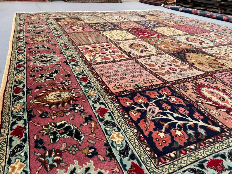 May include: A large rectangular area rug featuring a patchwork design of various square panels. Each square displays intricate floral, botanical, and bird motifs in a palette of deep red, navy blue, cream, pink, and sage green, framed by a wide border.