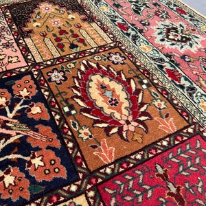 May include: A rectangular area rug featuring a patchwork design of various panels. The panels display intricate floral motifs, bird illustrations, and geometric patterns in vibrant shades of pink, navy blue, deep red, orange, and cream.