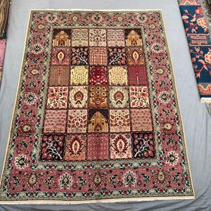 May include: A rectangular area rug featuring a central grid of twenty-five distinct square panels, each displaying unique floral and architectural motifs in shades of pink, red, navy blue, cream, and gold, framed by a wide, ornate pink border.