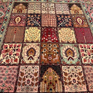 May include: A rectangular area rug featuring a grid of square panels, each decorated with intricate floral, botanical, and architectural motifs in shades of red, pink, cream, brown, and navy blue, framed by a wide, ornate floral border.